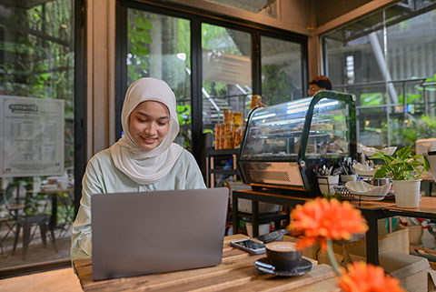 Female small business owner in her coffee shop using a laptop